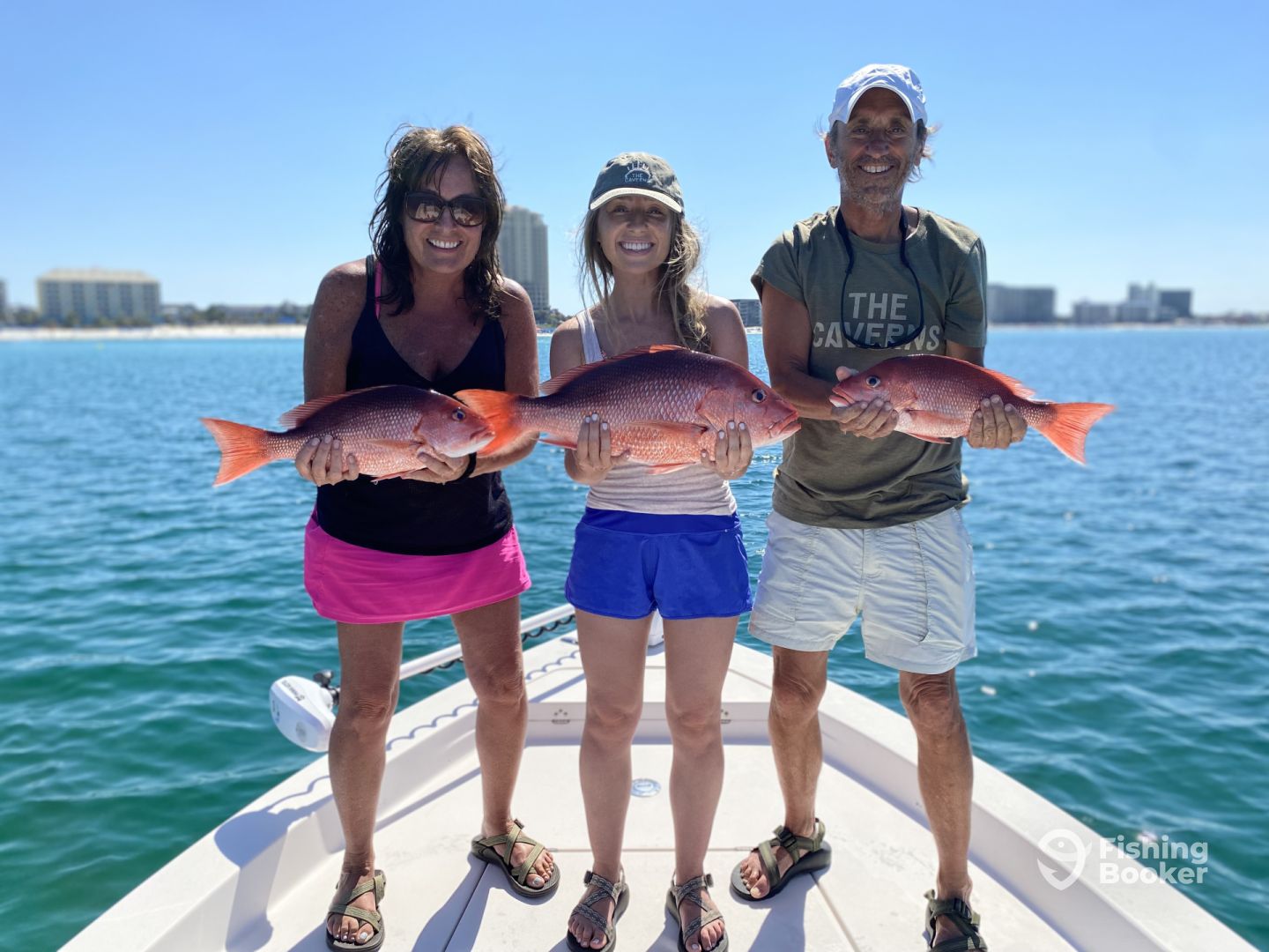 Three anglers holding red snapper aboard a fishing boat in clear Gulf water