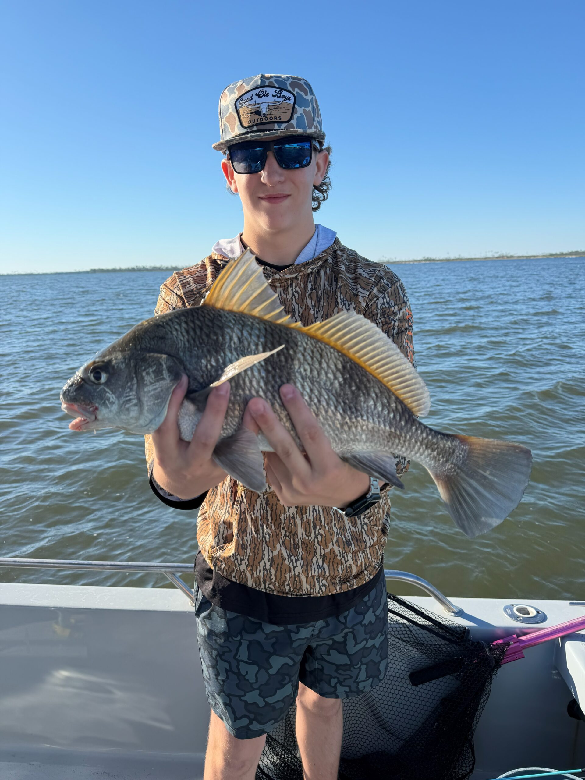 Young angler holding a fish aboard the boat on an earlier inshore trip